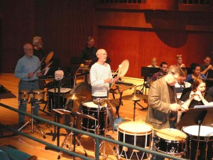 NEXUS playing paddle drums with the wind ensemble