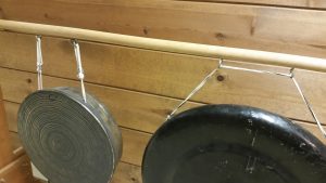 Photo 1 - Closeup view of screw hooks on a wooden rail supporting gongs